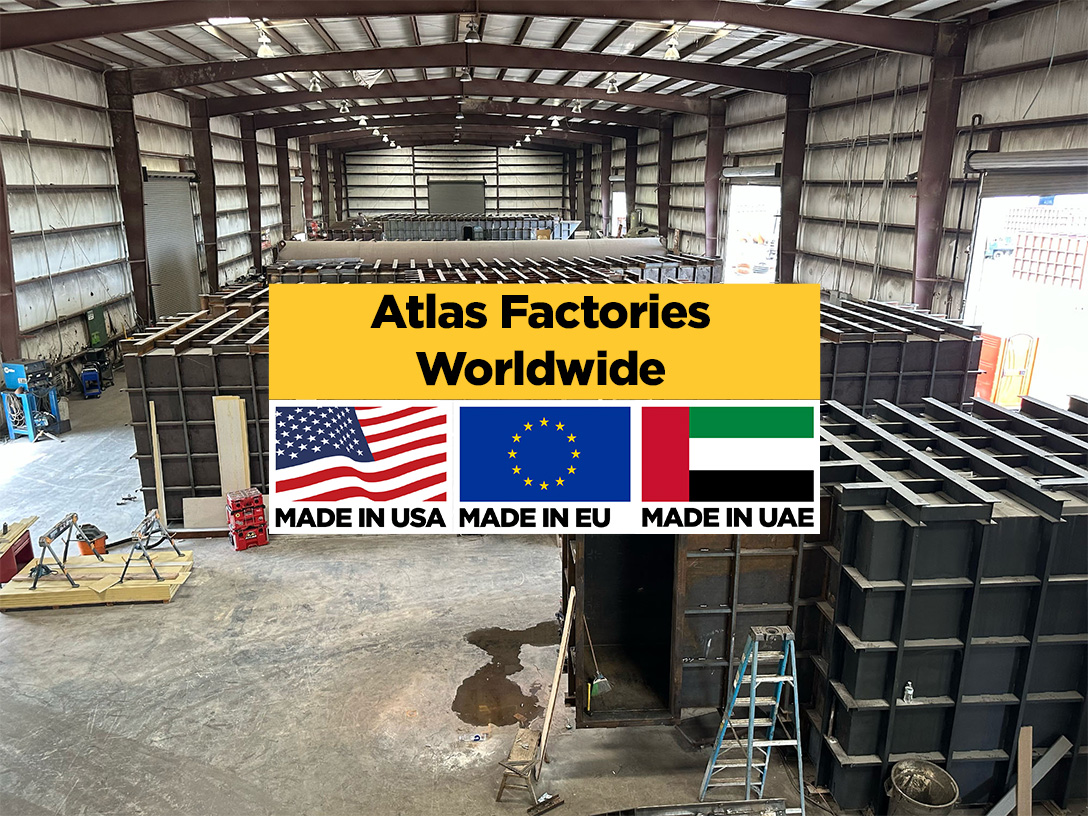 Industrial warehouse with a large yellow banner reading 'Atlas Factories Worldwide' and flags for USA, EU, and UAE at the front.