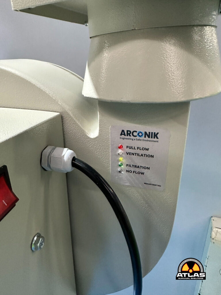 Close-up of an Arconik air processing unit control panel with colored status LEDs (Full Flow, Ventilation, Filtration, No Flow) and a black power cable.