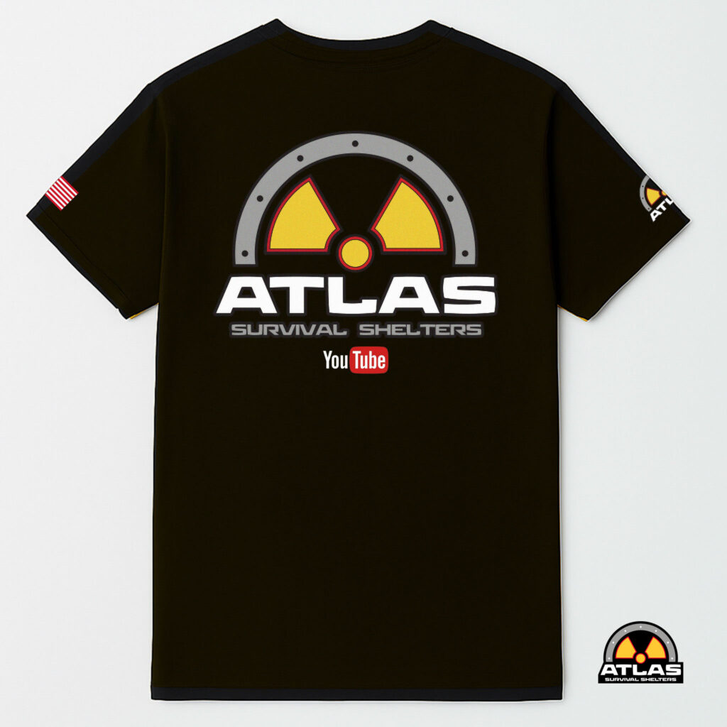 Back view of a black T-shirt featuring a large gray circular hazard emblem with yellow/red radiation symbol and the words ATLAS SURVIVAL SHELTERS on the lower back area.