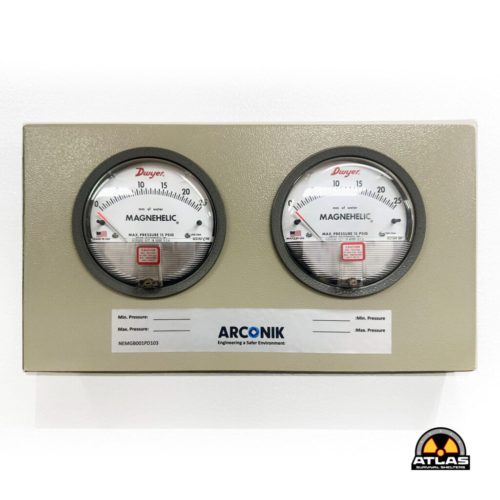 Two Magnehelic differential pressure gauges mounted on a beige panel, with Atlas Survival Shelters logo visible in the bottom-right corner of the image.
