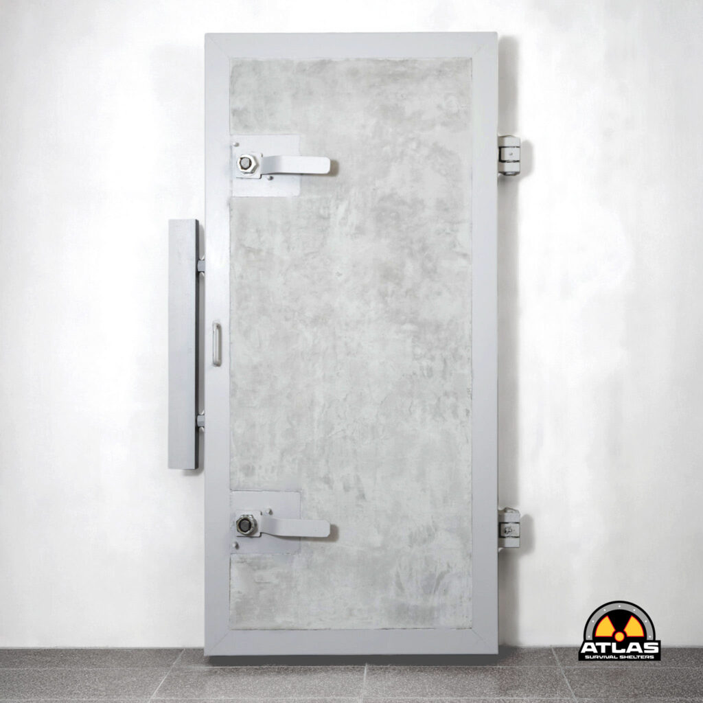 Tall gray metal vault door set in a white wall with a horizontal lever latch and side hinges; Atlas Survival Shelters logo visible in the bottom-right corner.