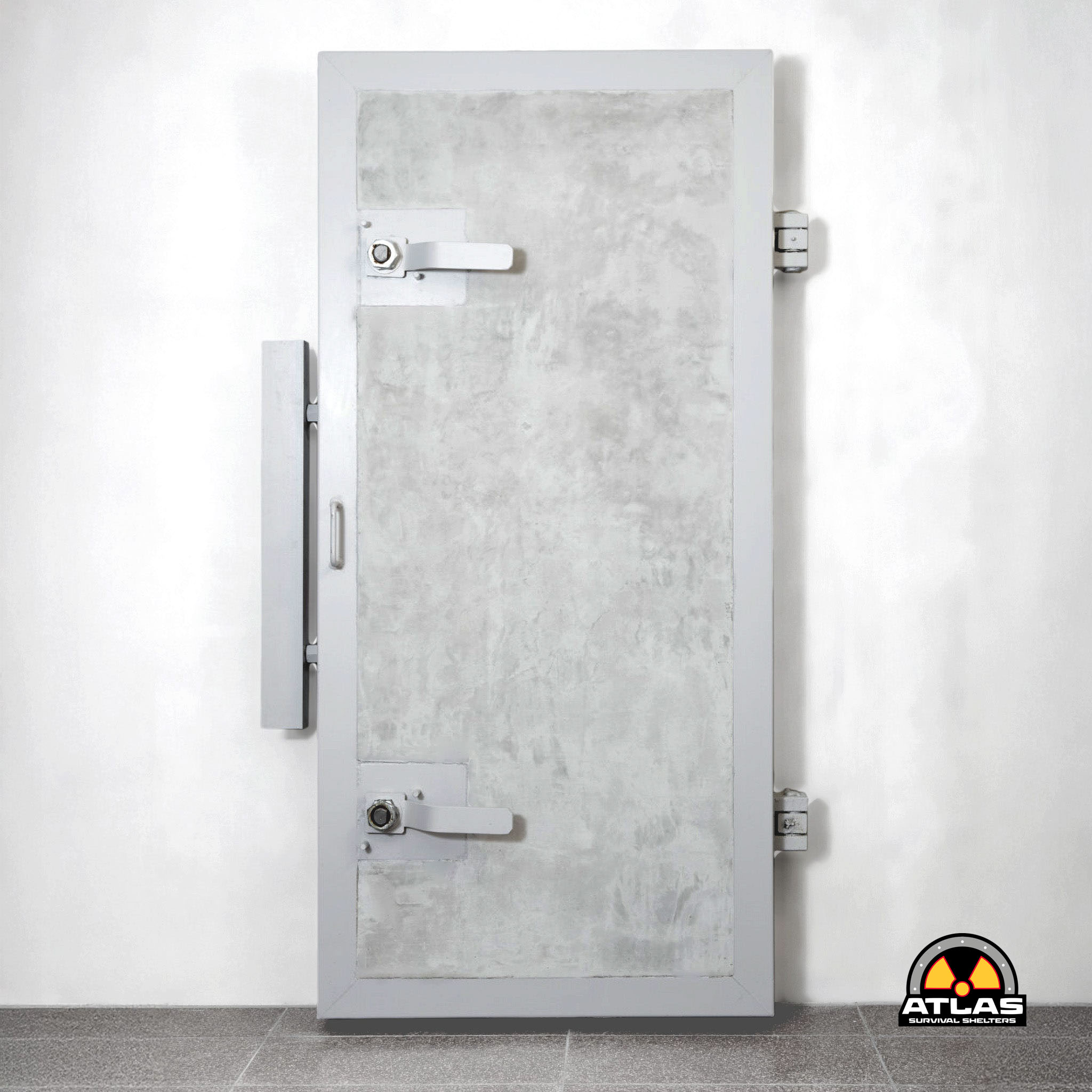 Tall gray metal vault door set in a white wall with a horizontal lever latch and side hinges; Atlas Survival Shelters logo visible in the bottom-right corner.