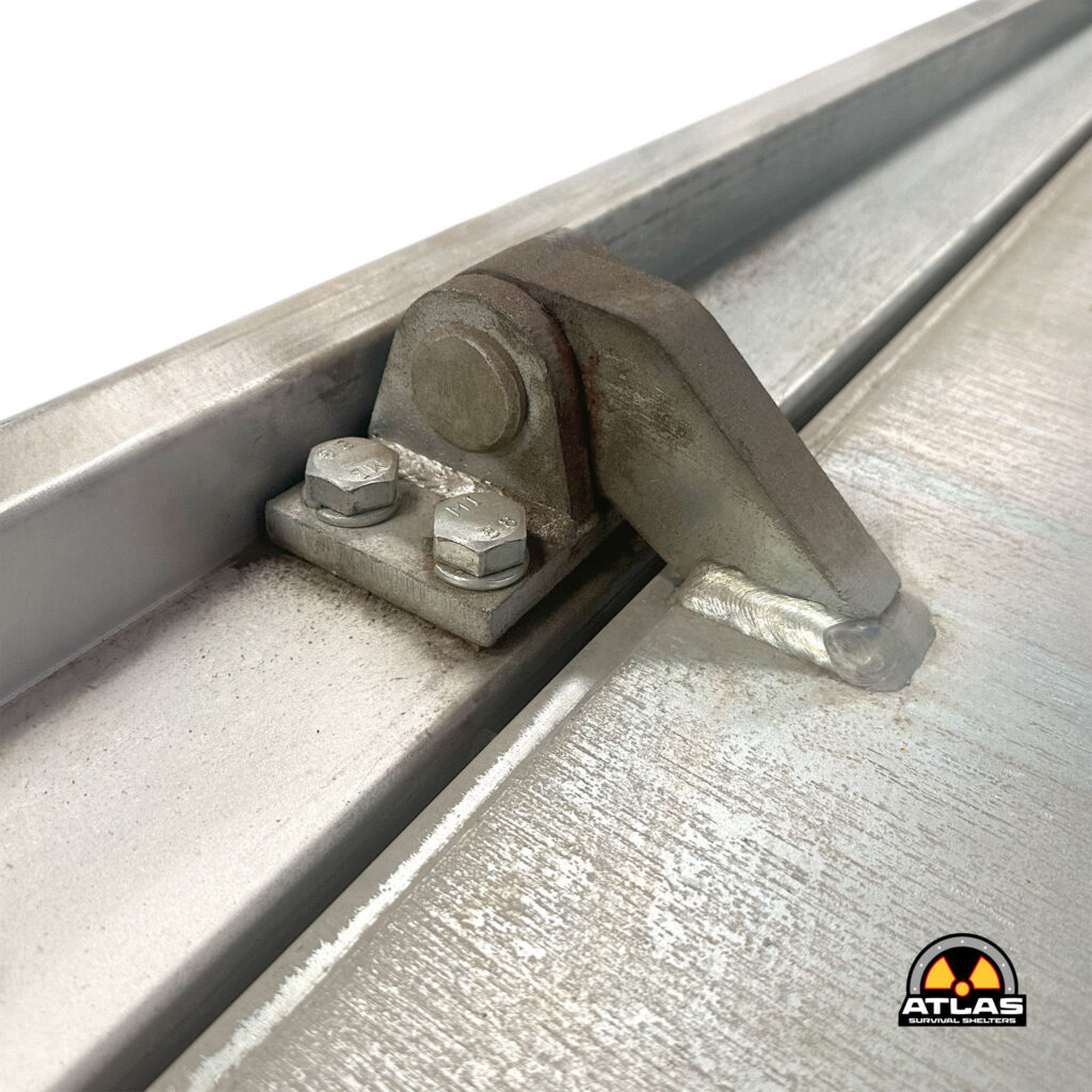 Close-up of a diagonal metal track with bolts and a rusted plate; Atlas Survival Shelters logo visible bottom-right.