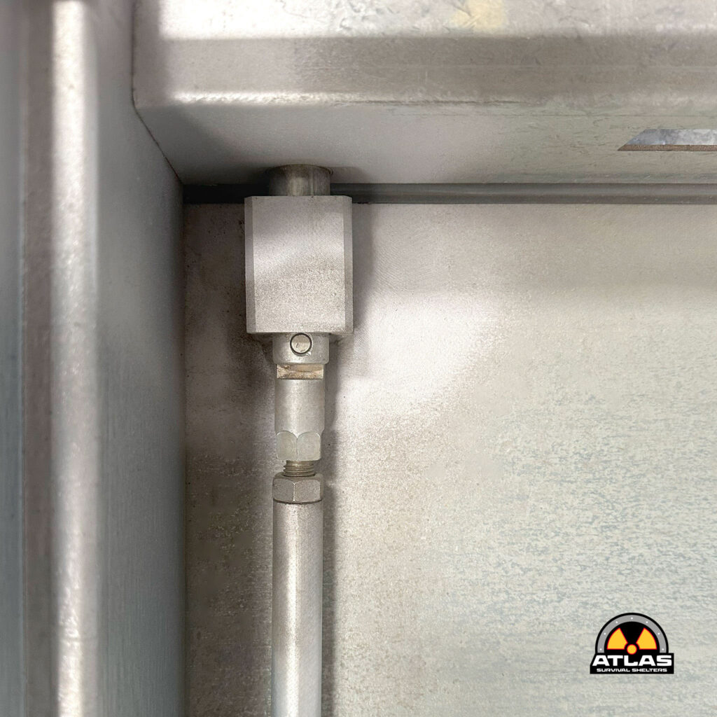 Industrial metal pipes in a corner against a concrete wall with a radiation warning sticker visible in the bottom-right corner.