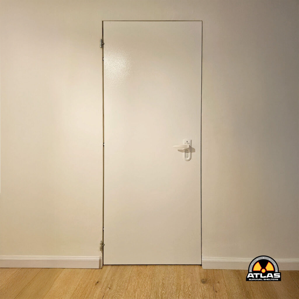 White interior door set in a light-colored wall, with a hinge on the left and a lever handle on the right; watermark logo in the bottom-right corner reads ATLAS Survival Shelters.