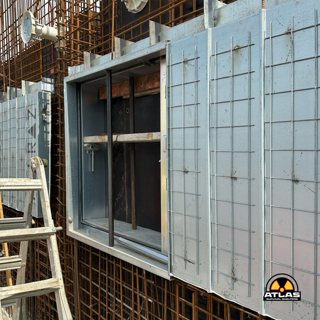 Construction site showing exposed rebar and concrete formwork panels with scaffold and a radiation warning logo in the corner.